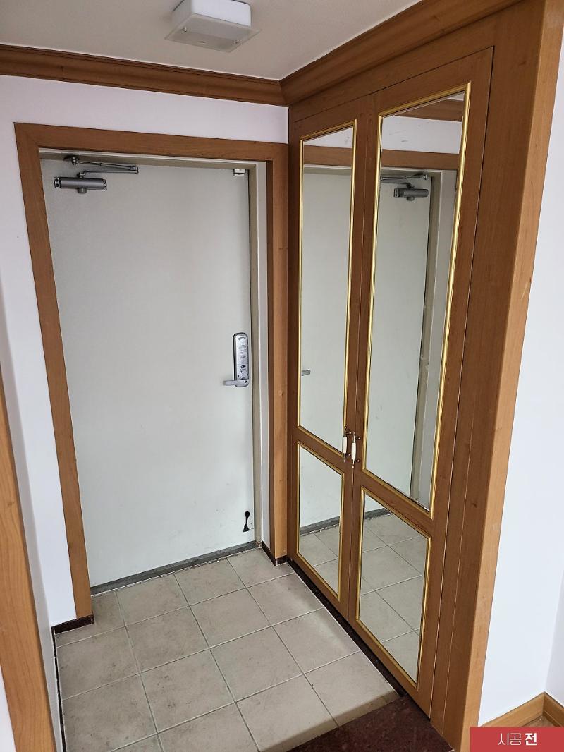 시공 전 나무 테두리 문틀이 보이는 현관 공간