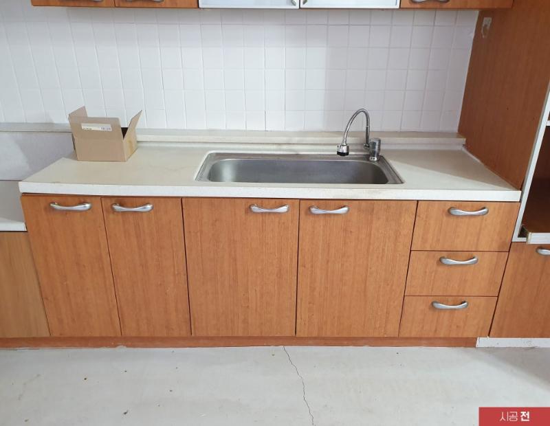 백색 타일 벽면과 목재 상부장이 맞닿은 시공 전 모습