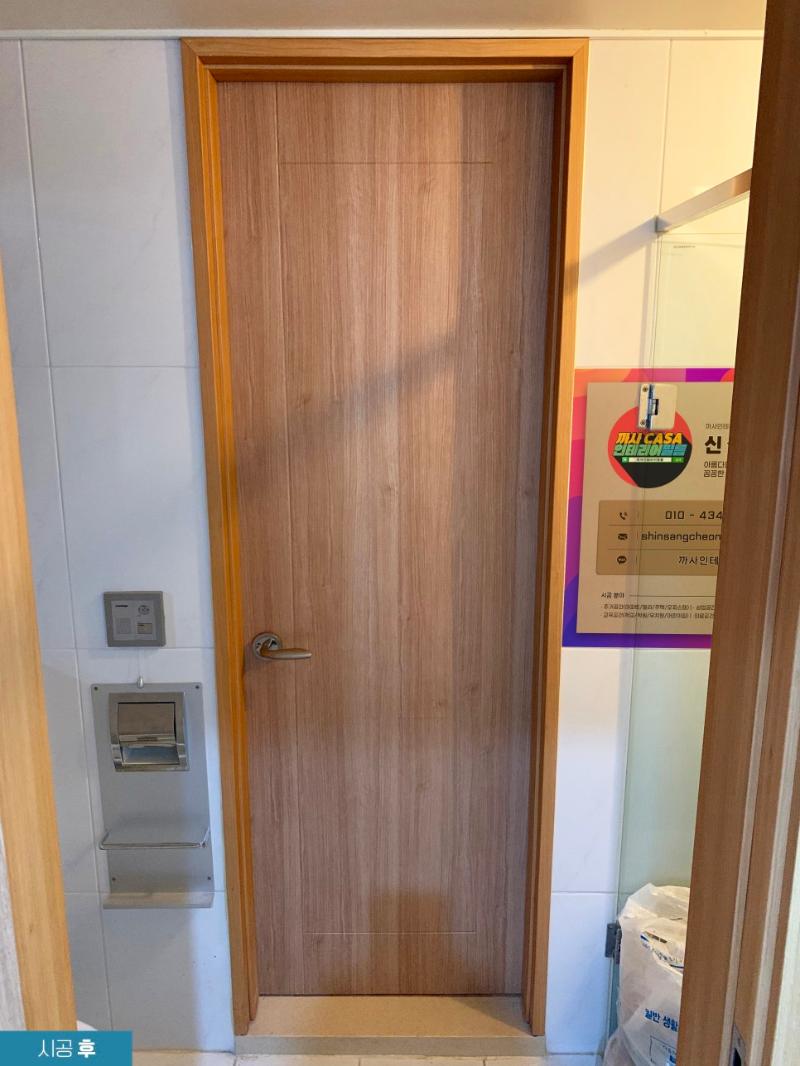 흰색 타일 벽면과 리폼된 도어가 보이는 현관 공간