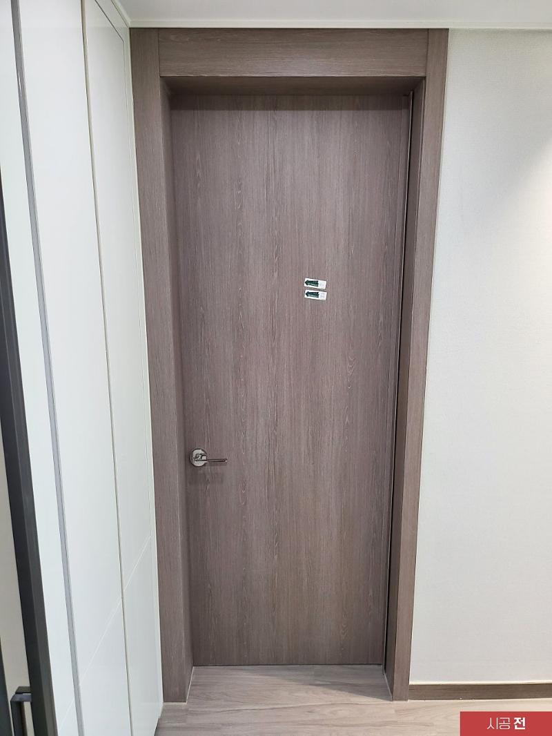 갈색 목재 패턴의 문이 설치된 시공 전 현관