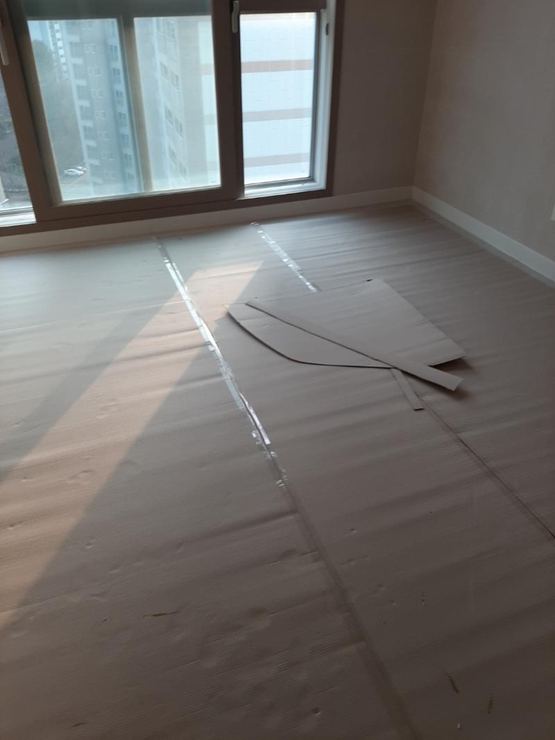 창문 근처 바닥재 위 테이프와 종이 조각