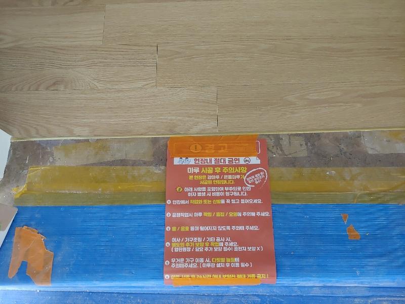 파란색 보호재와 노란색 테이프로 마감 처리된 벽면
