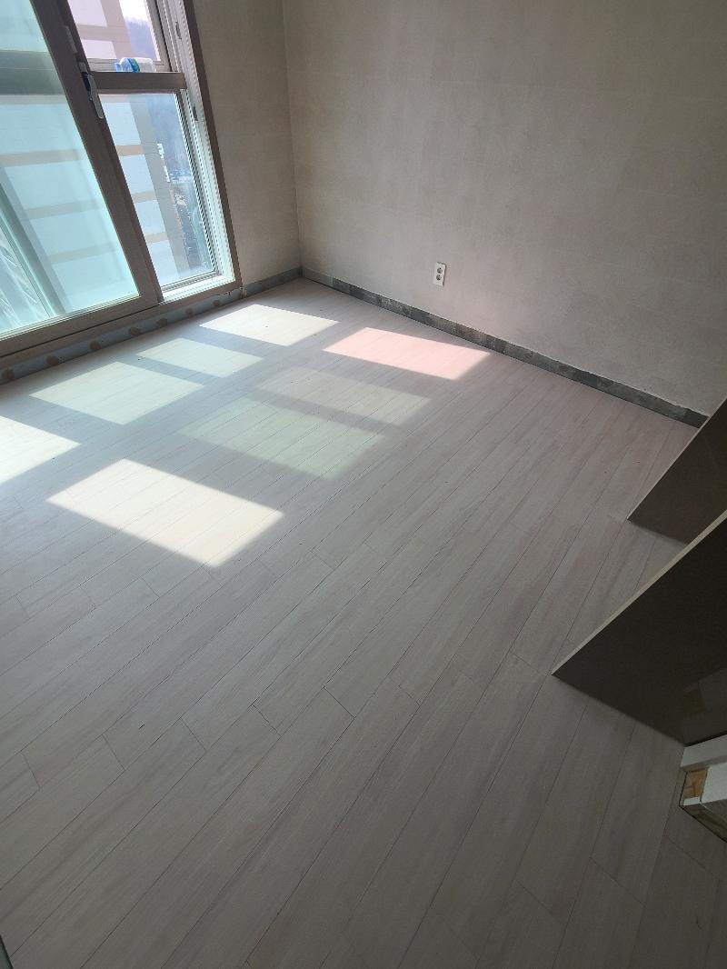 흰색 벽지와 바닥재가 접합된 벽면 하단