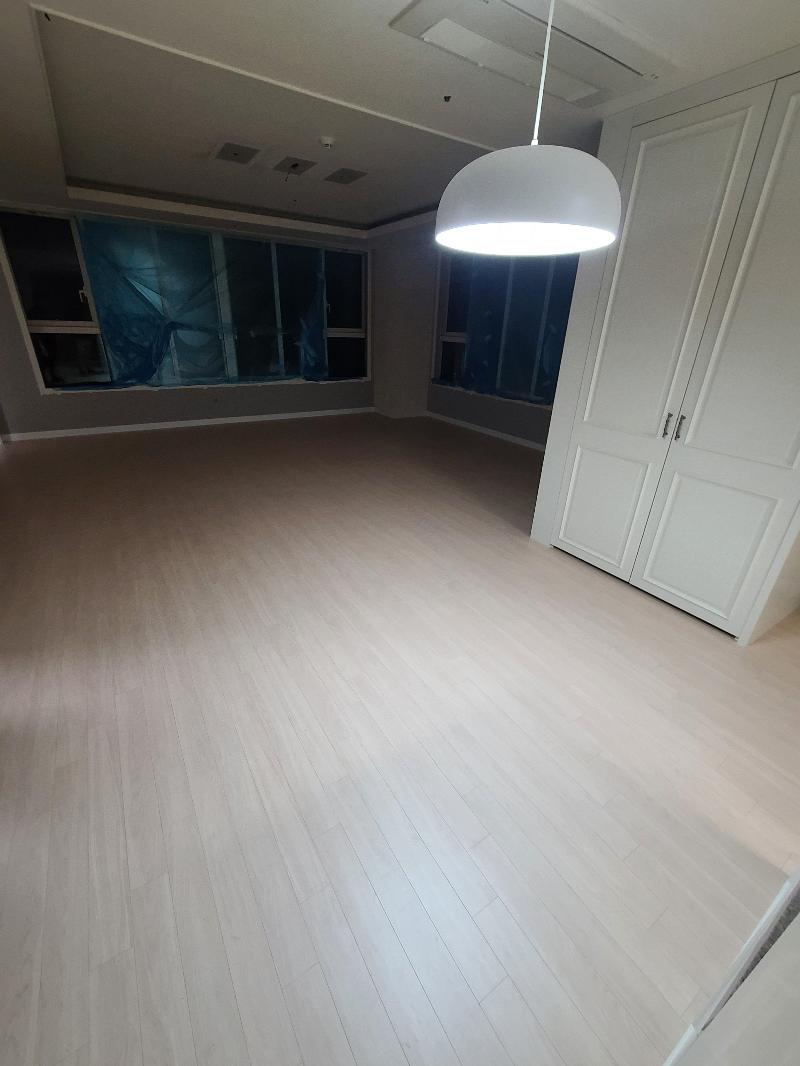 회색 벽면과 원형 조명이 있는 공간의 밝은 목재 바닥
