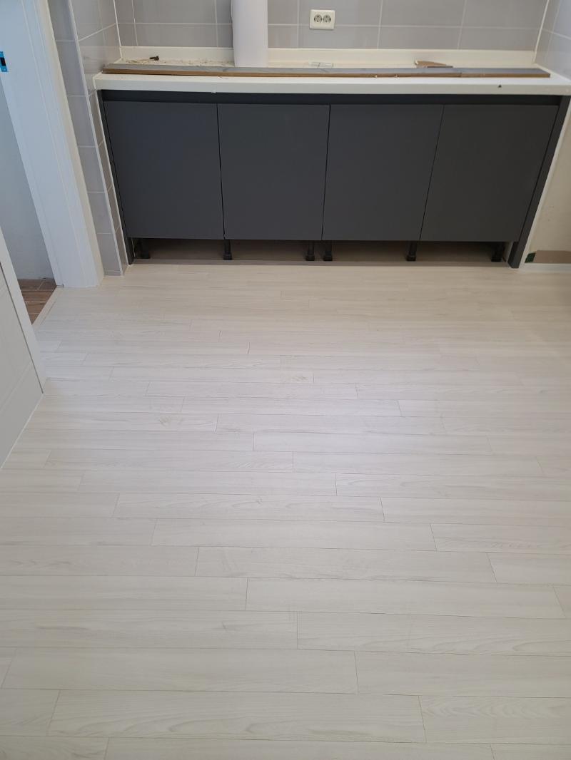 회색 타일 벽과 수납장이 설치된 주방 바닥의 마감 상태