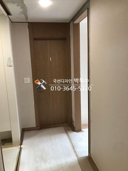 베이지색 벽지와 갈색 도어가 설치된 복도