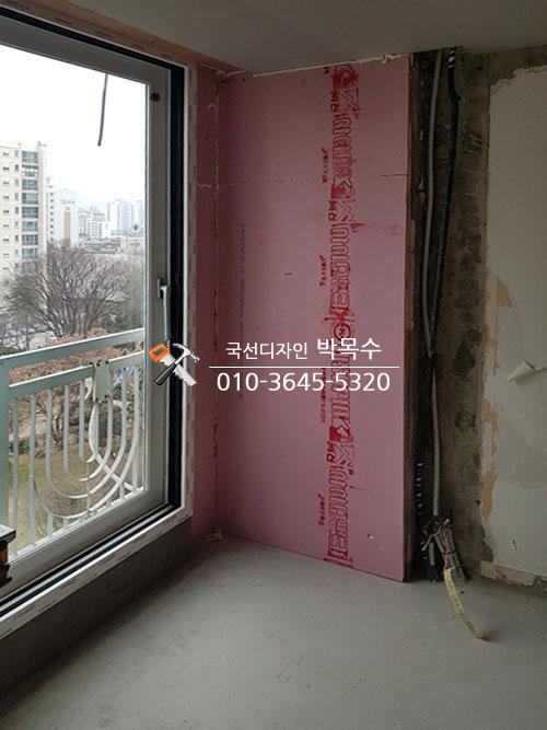 분홍색 보온재가 설치된 발코니 외벽과 흰색 난간