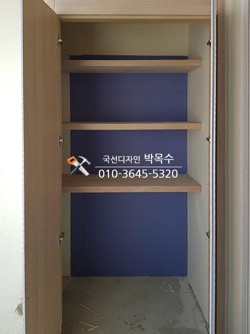 파란색 보드 위에 나무 선반 3개가 설치된 공간