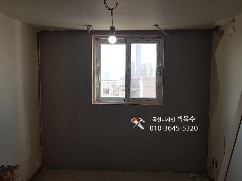 회색 마감 벽면 중앙에 설치된 창호와 임시 전등