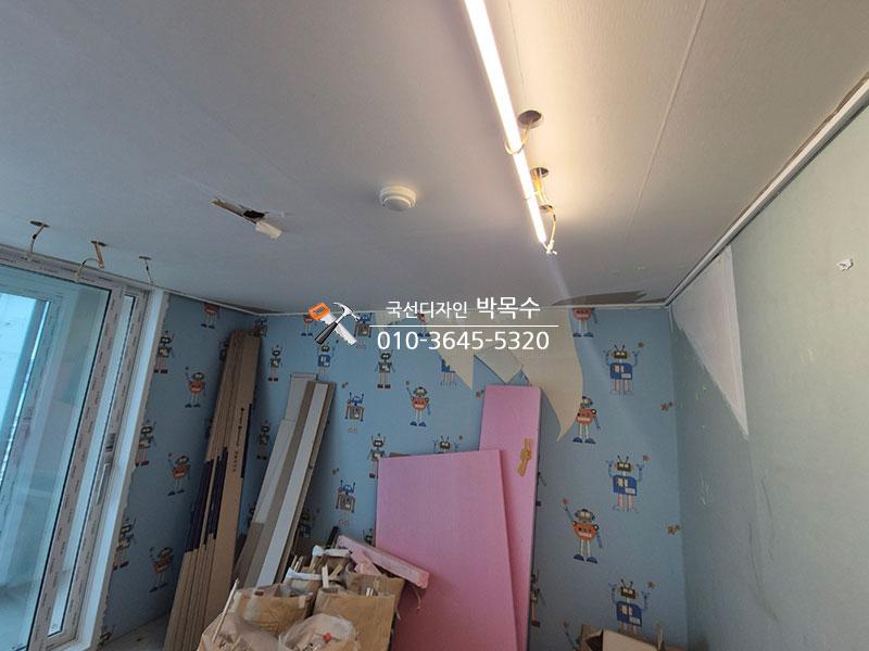 파란색 벽지와 공사 자재들이 놓인 천장 작업 구간