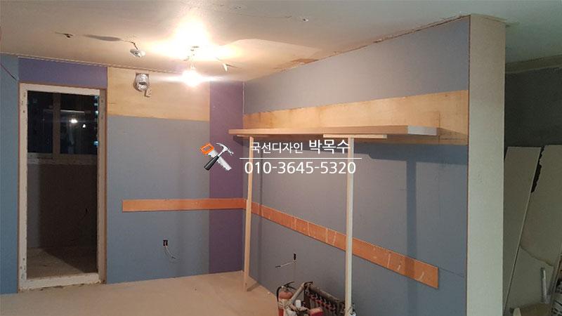 나무 재질의 무지주선반과 도색된 벽면이 보이는 공간