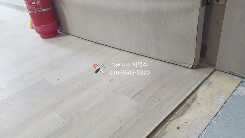 바닥재가 깔린 공간의 흰색 도어와 벽면