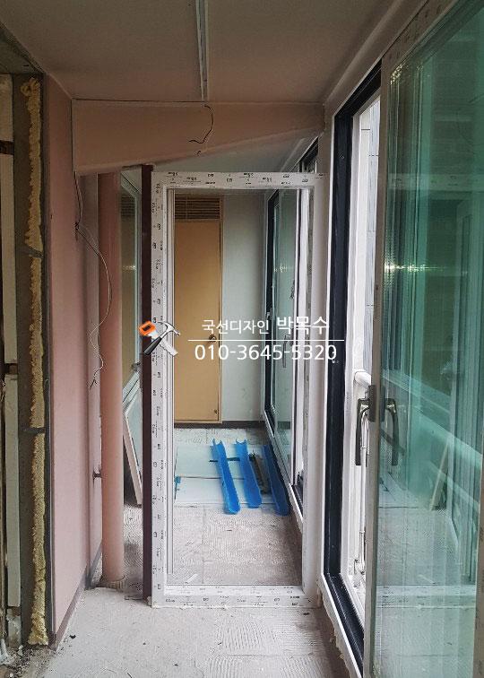 문틀과 문짝이 설치되고 있는 흰색 콘크리트 바닥의 복도