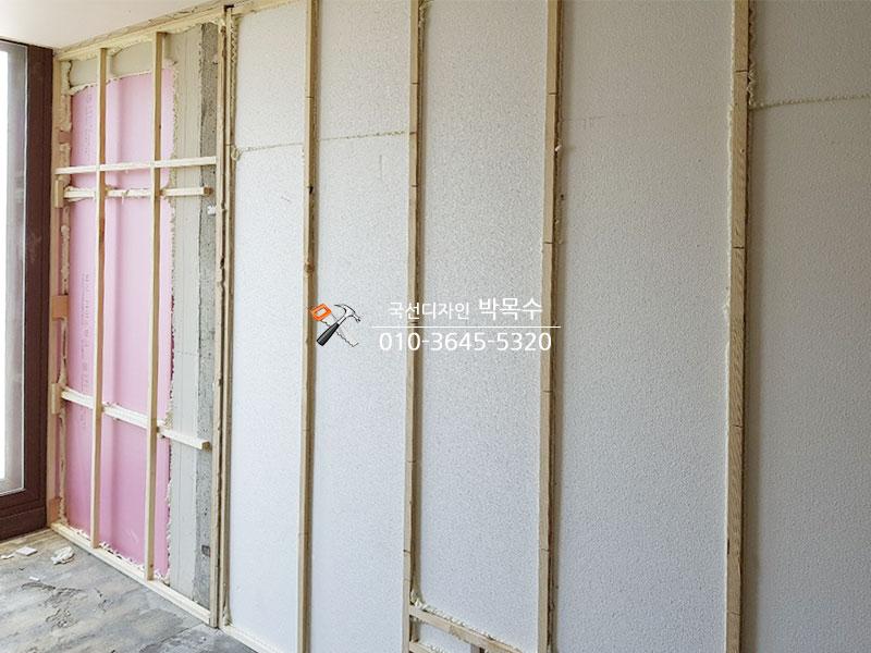 벽면에 설치된 목재 프레임과 핑크색 보조재