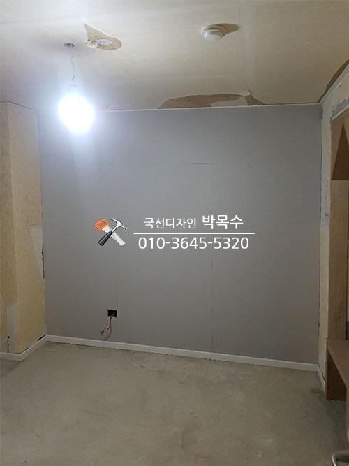 회색 마감 벽면과 전기 소켓, 목재 구조물이 보이는 모습