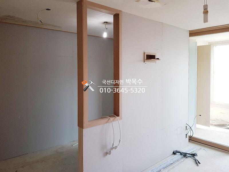 나무 프레임과 흰색 마감재가 설치 중인 실내 공간