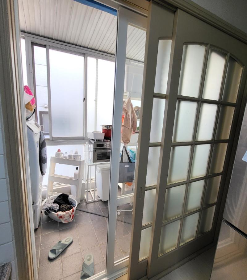 슬라이딩 도어 너머로 보이는 세탁기와 타일 바닥 공간