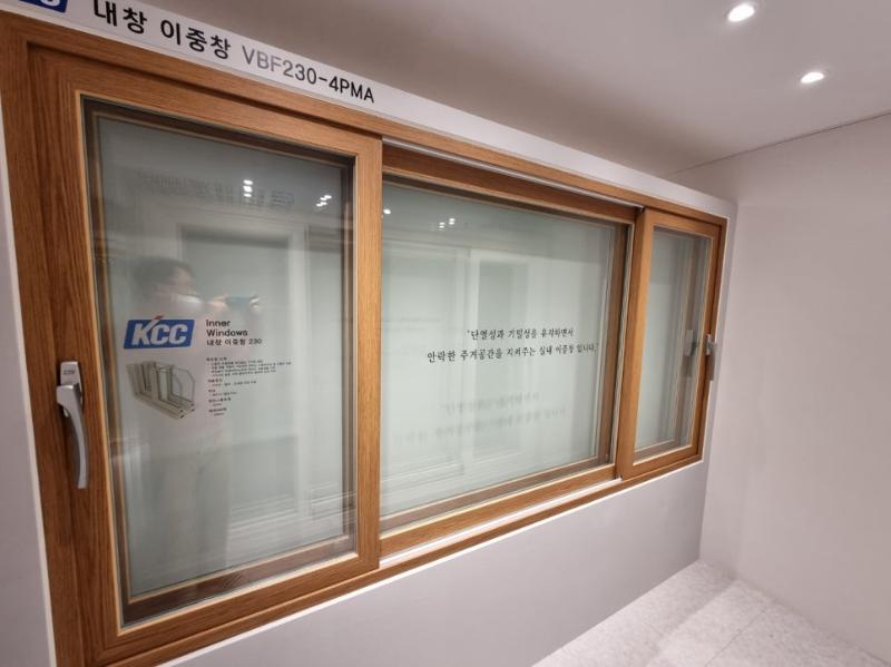 흰색 벽면에 설치된 목재 질감 프레임의 내창 이중창