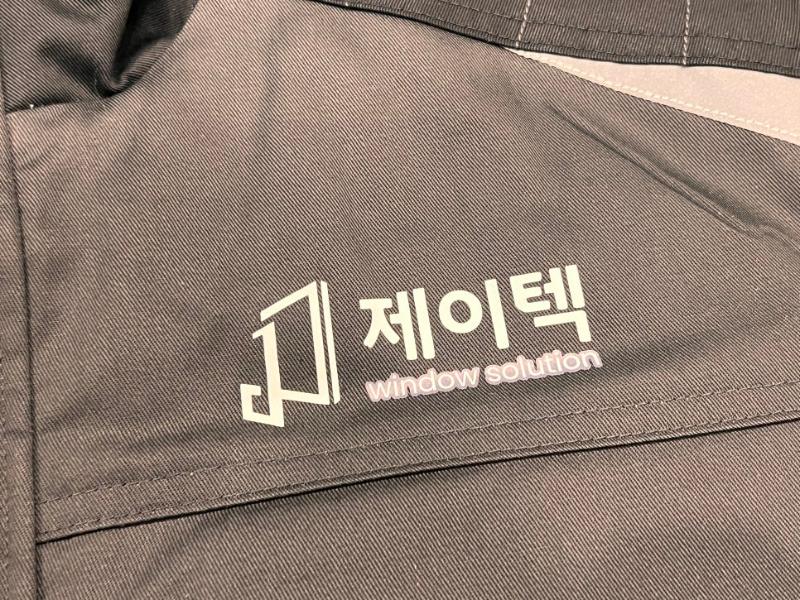 검정색 직물 소재 위 제이텍 로고와 문구