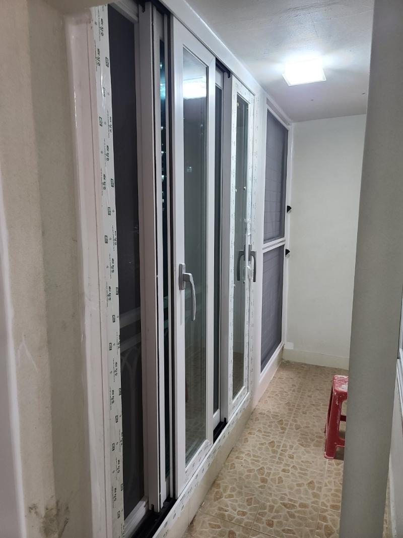 베이지색 타일 바닥과 흰색 슬라이딩 창호가 설치된 복도