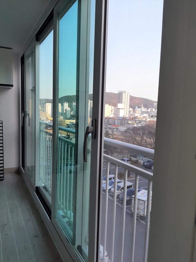 회색 타일 바닥과 흰색 난간이 보이는 발코니 창호