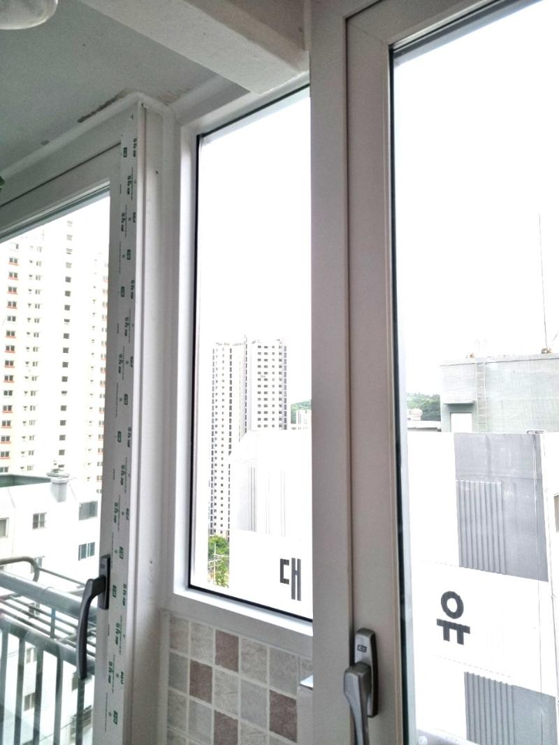 외부 건물이 비치는 흰색 프레임의 창호 근접샷