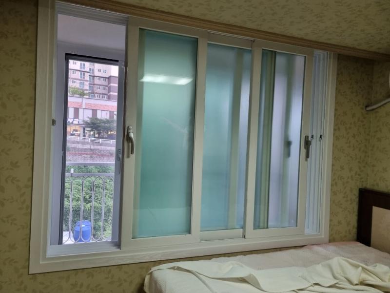벽지 도배와 침대가 보이는 침실의 창호 근접 샷