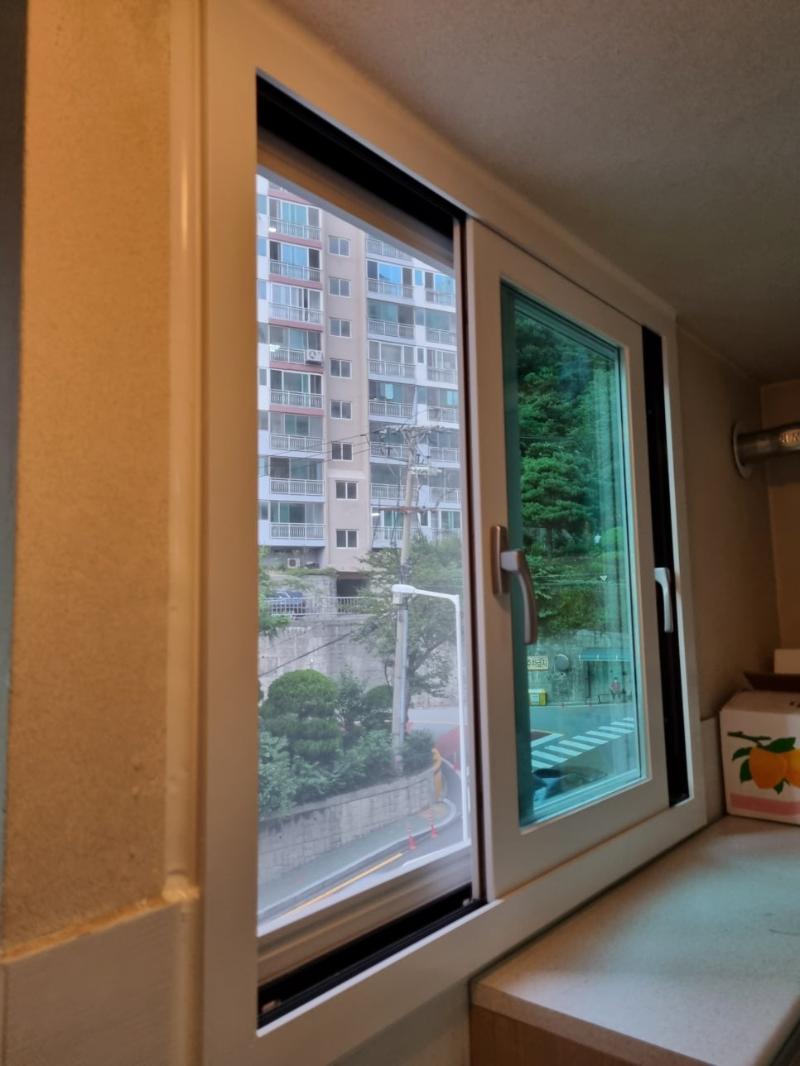 창문 프레임과 유리 패널, 외부 나무가 보이는 근접 샷