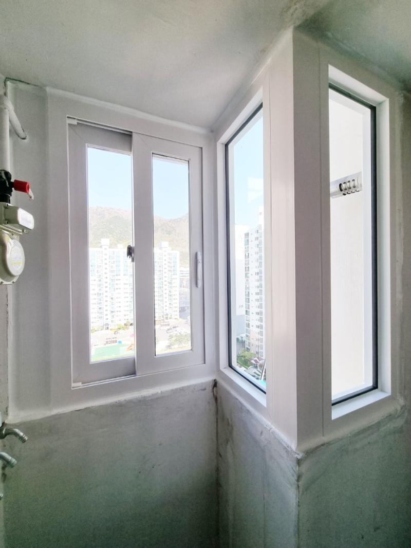 흰색 프레임 창호와 수도관, 화재 경보기가 보이는 벽면