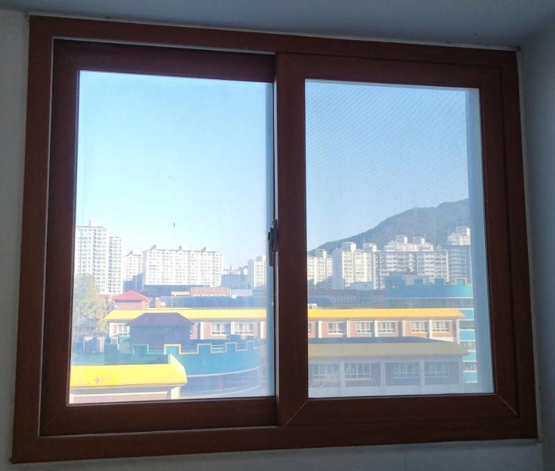 창호 프레임 너머로 산과 건물이 보이는 외부 풍경