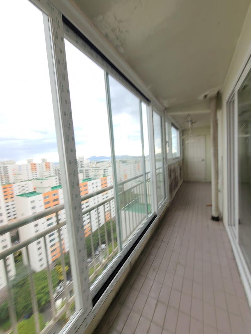 베이지색 타일 바닥과 흰색 프레임 창호가 설치된 발코니