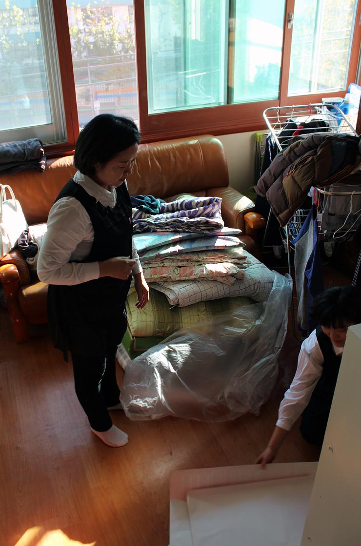 가죽 소파와 이불이 놓인 거실의 정리 전 모습