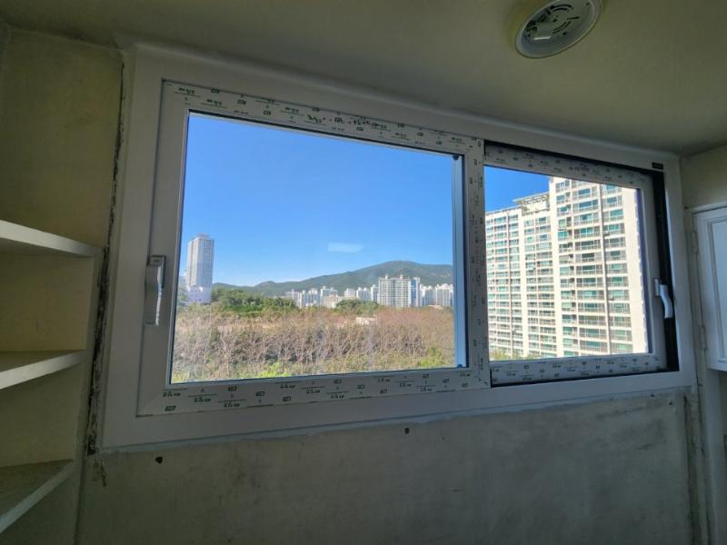 고층 건물과 산이 보이는 흰색 프레임의 창호 패널