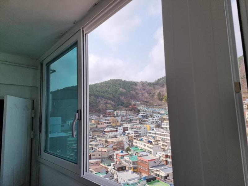 창문이 열린 상태로 외부 산과 건물이 보이는 실내 창호