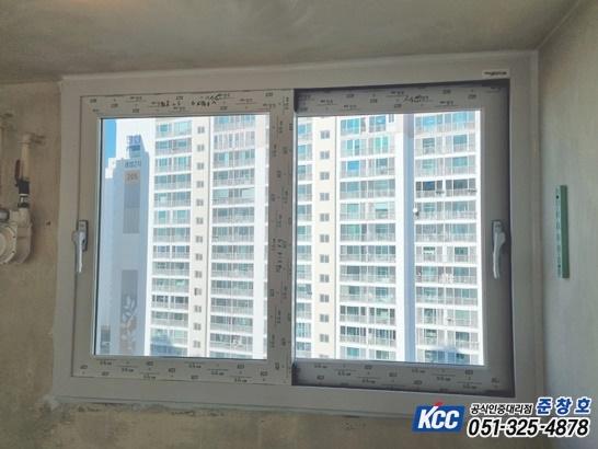 실내에서 바라본 흰색 프레임의 창호와 외부 건물