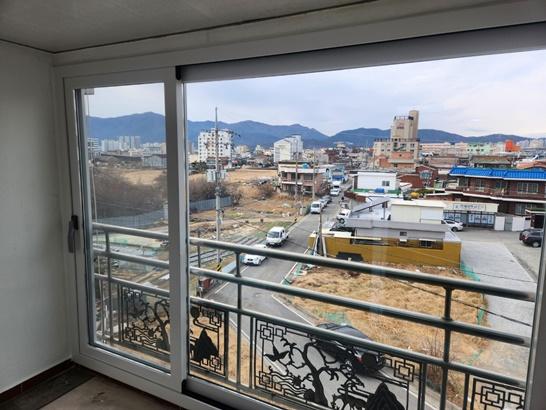외부 도로와 산이 배경으로 보이는 유리문과 금속 난간