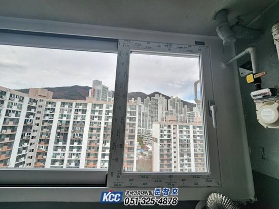 열린 창 너머로 보이는 고층 아파트와 산의 풍경