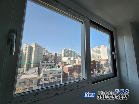창문 외부로 고층 아파트와 저층 건물이 보이는 실내 창가